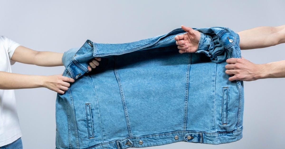 Two individuals pulling on a blue denim jacket, highlighting fashion and tension.